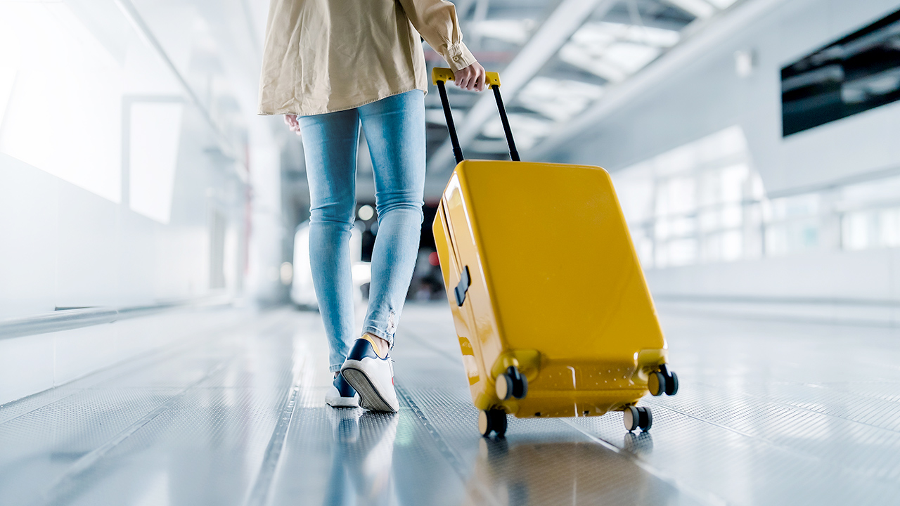 Mujer arrastrando una maleta de mano por un aeropuerto- Reglamento de viajeros